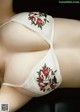 A woman wearing a white bra with red flowers on it.