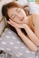 A woman laying on a bed with her eyes closed.
