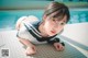 A woman in a sailor outfit laying on the edge of a swimming pool.