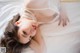 A woman laying on a bed in a white lingerie.